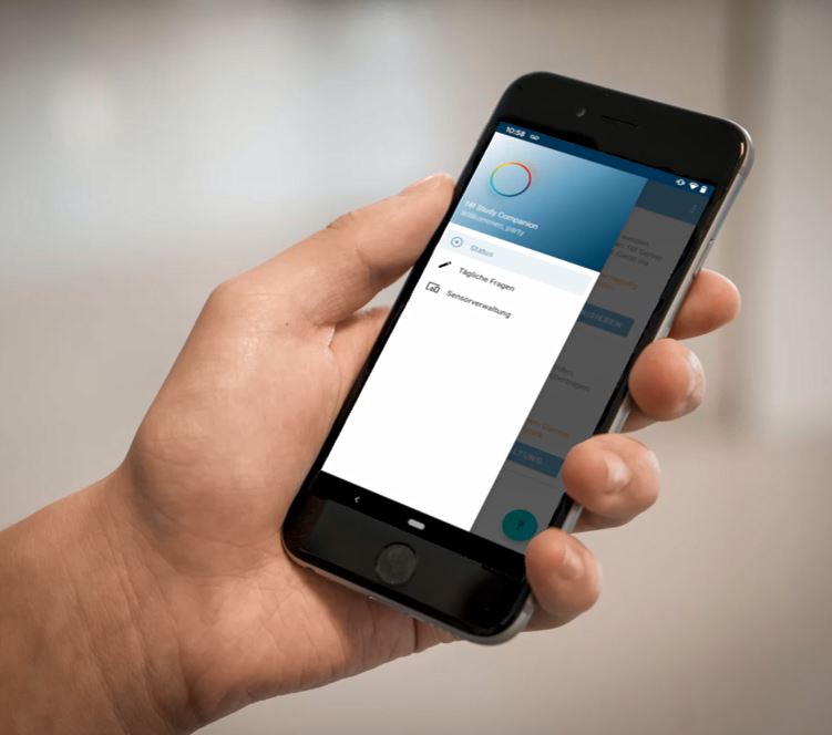 Eine Hand hält ein Smartphone, auf der die food4future-App läuft. Man sieht das kreisförmige F4F-Logo und Einstellungen