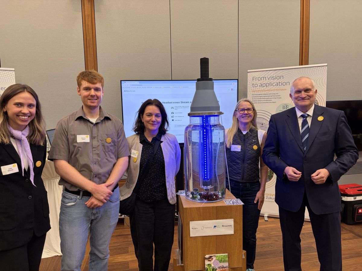 Gemeinsam am food4future-Stand in Brüssel: Jette Berend, Marino Gabel, Stefanie Fleischmann, Monika Schreiner und Christoph M. Schmidt, Präsident der Leibniz-Gemeinschaft (v. l. n. r.), vor dem ausgestellten Algenreaktor.